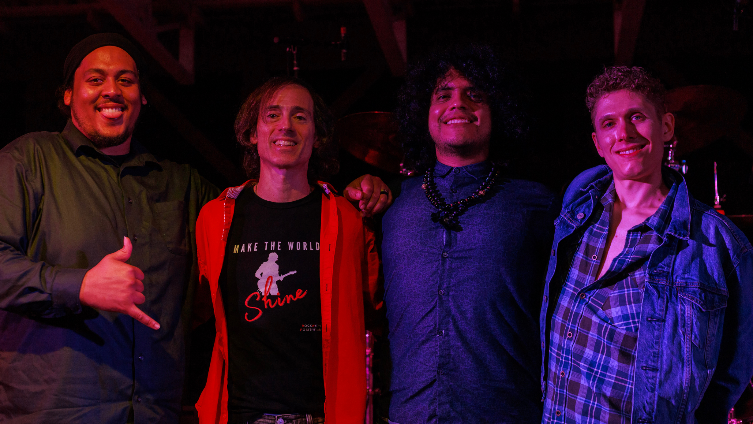 Four smiling musicians posing together on stage