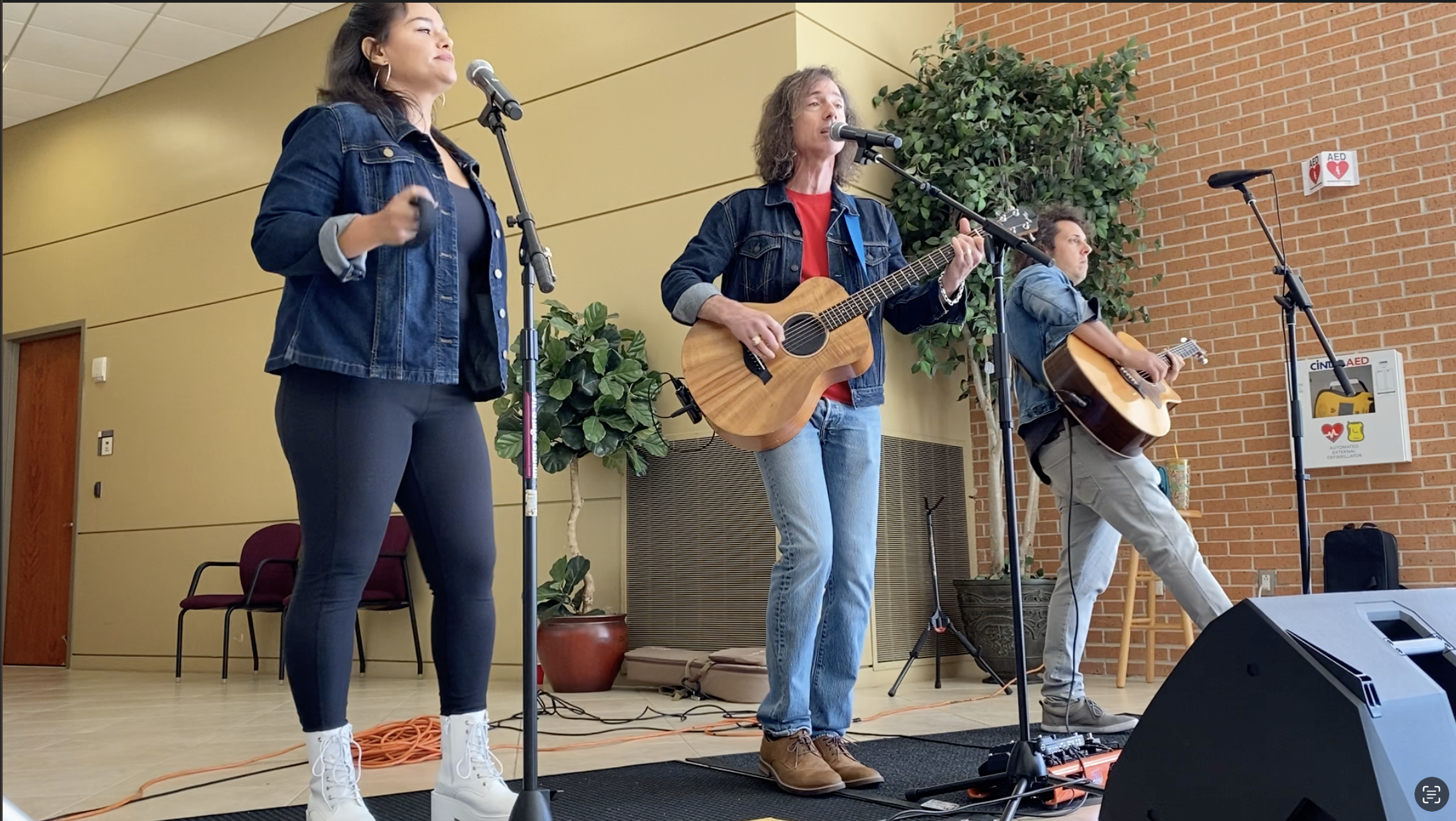 Three musicians performing indoors with acoustic guitars