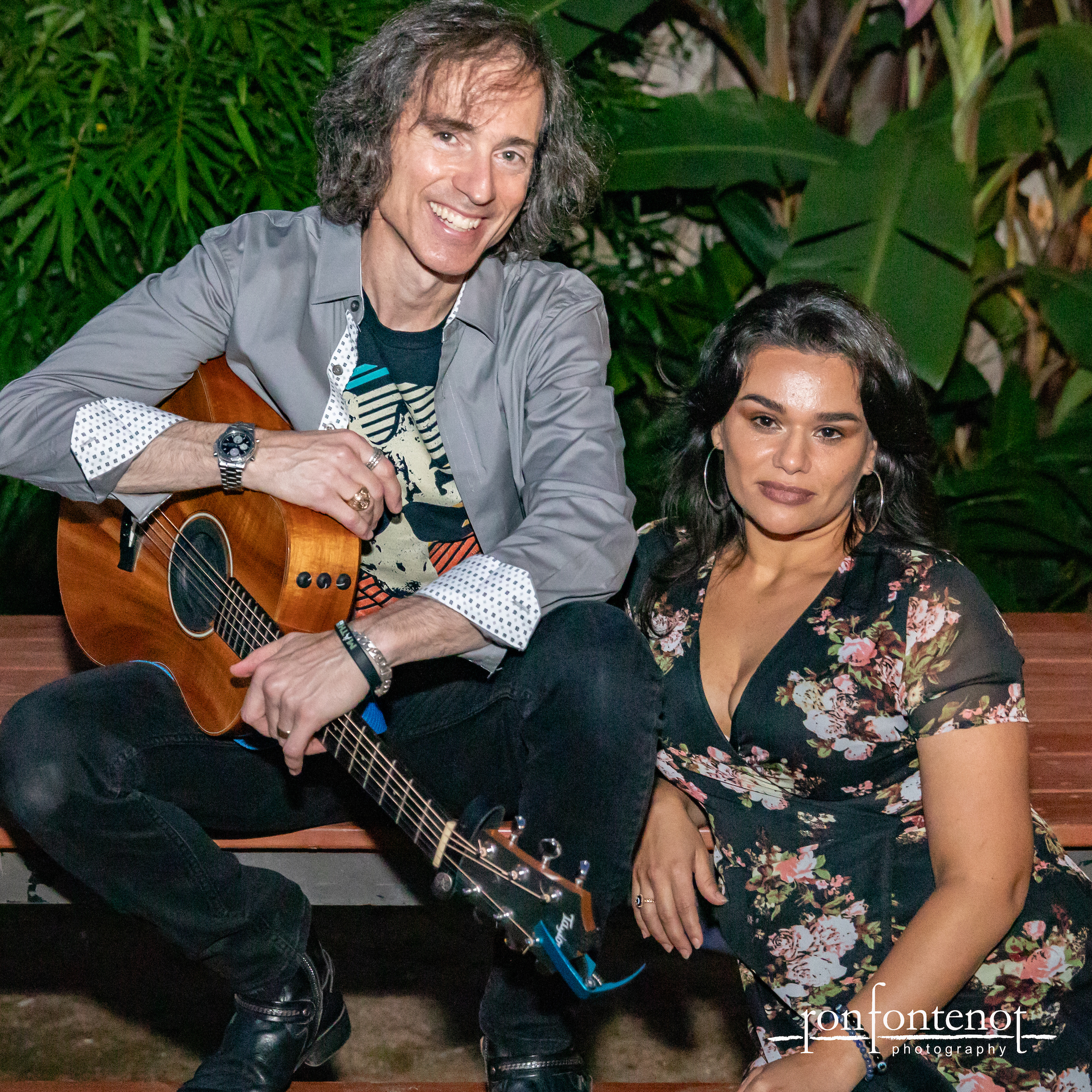 Two musicians posing with acoustic guitar outdoors