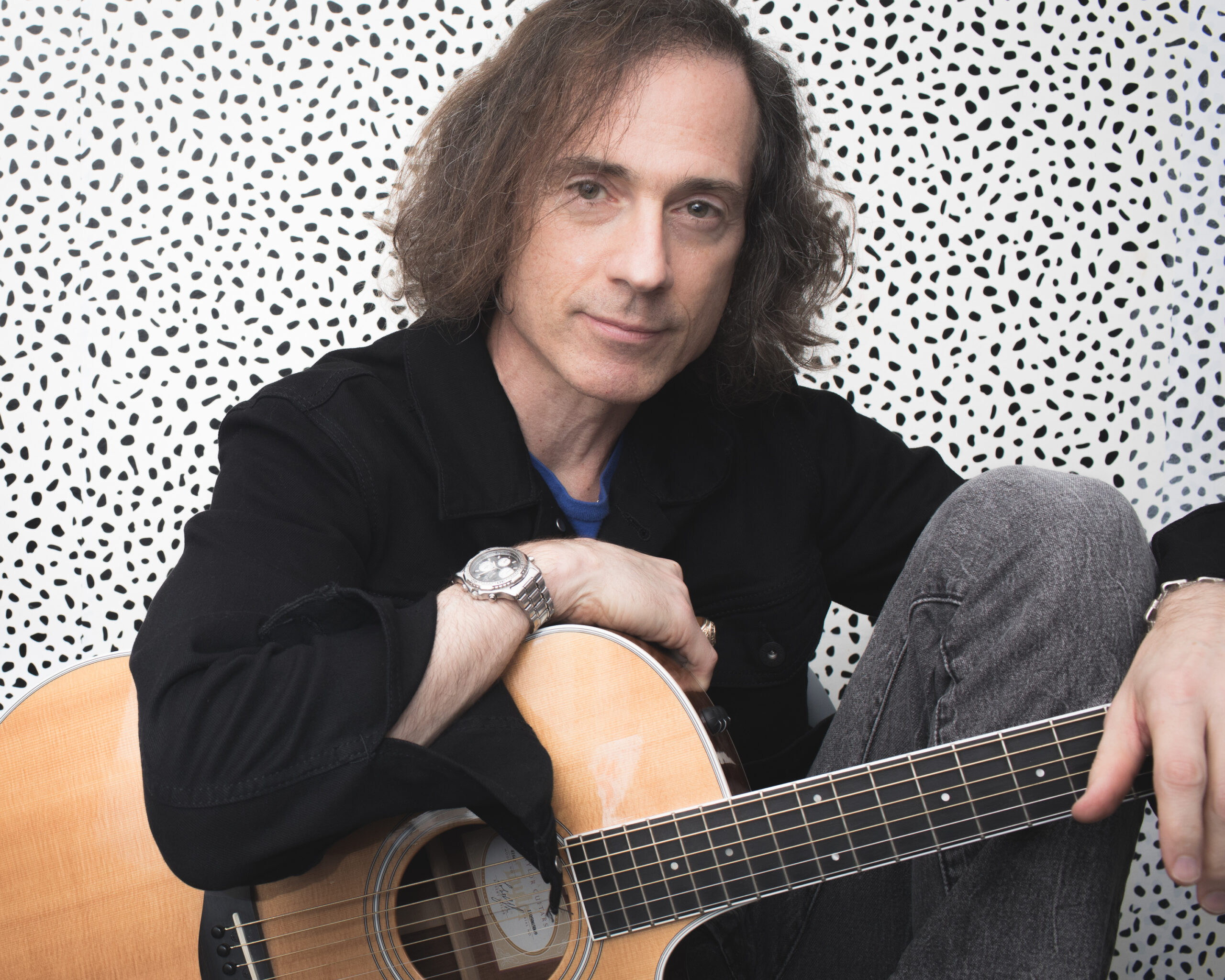 Man seated holding acoustic guitar