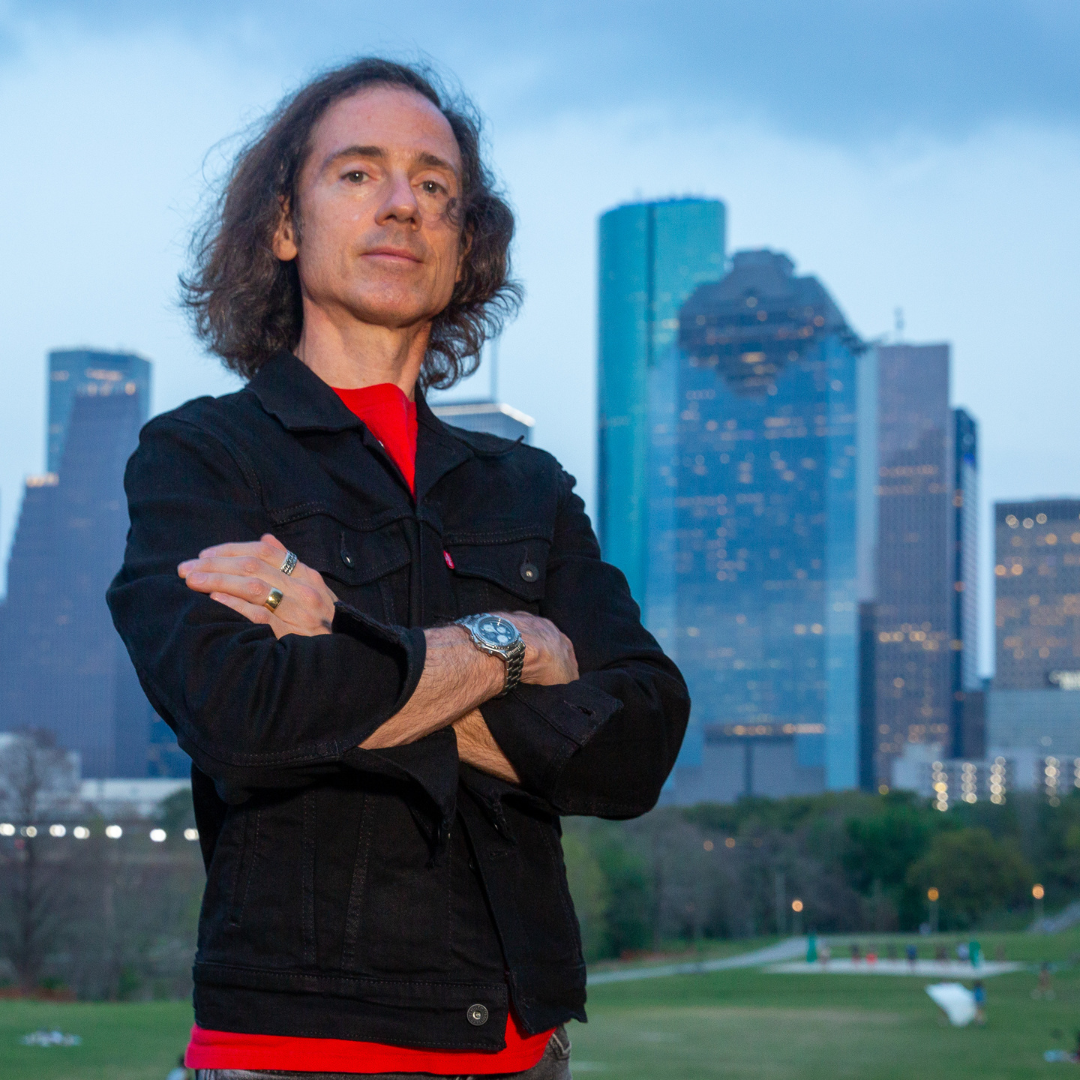 Person standing with crossed arms in city park