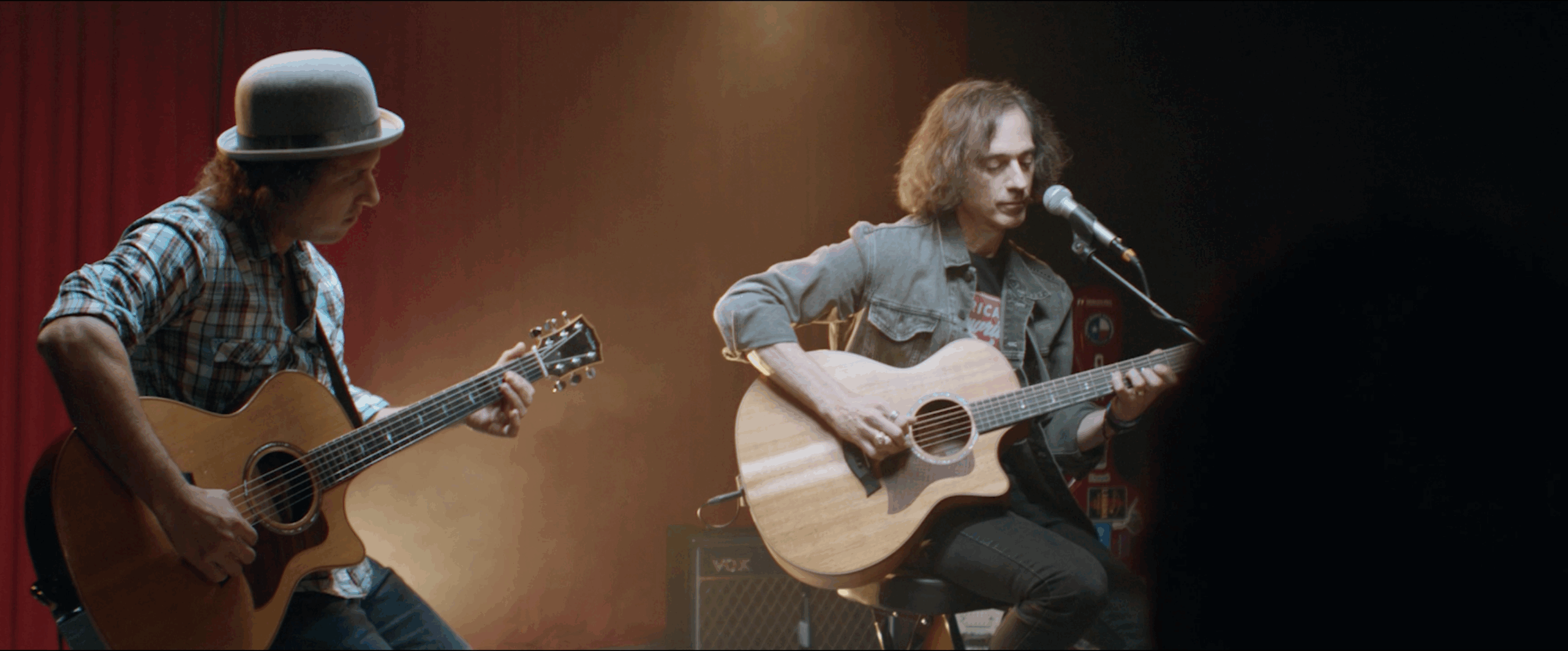 Two musicians playing acoustic guitars on stage